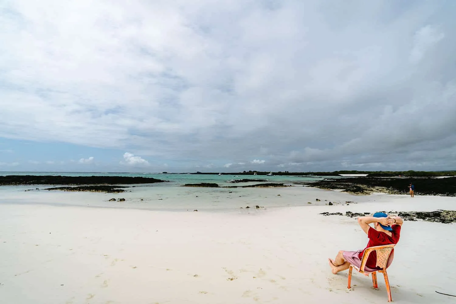 Sitting on a plastic chair at Bahia Rosa Blanca beach in San Cristobal