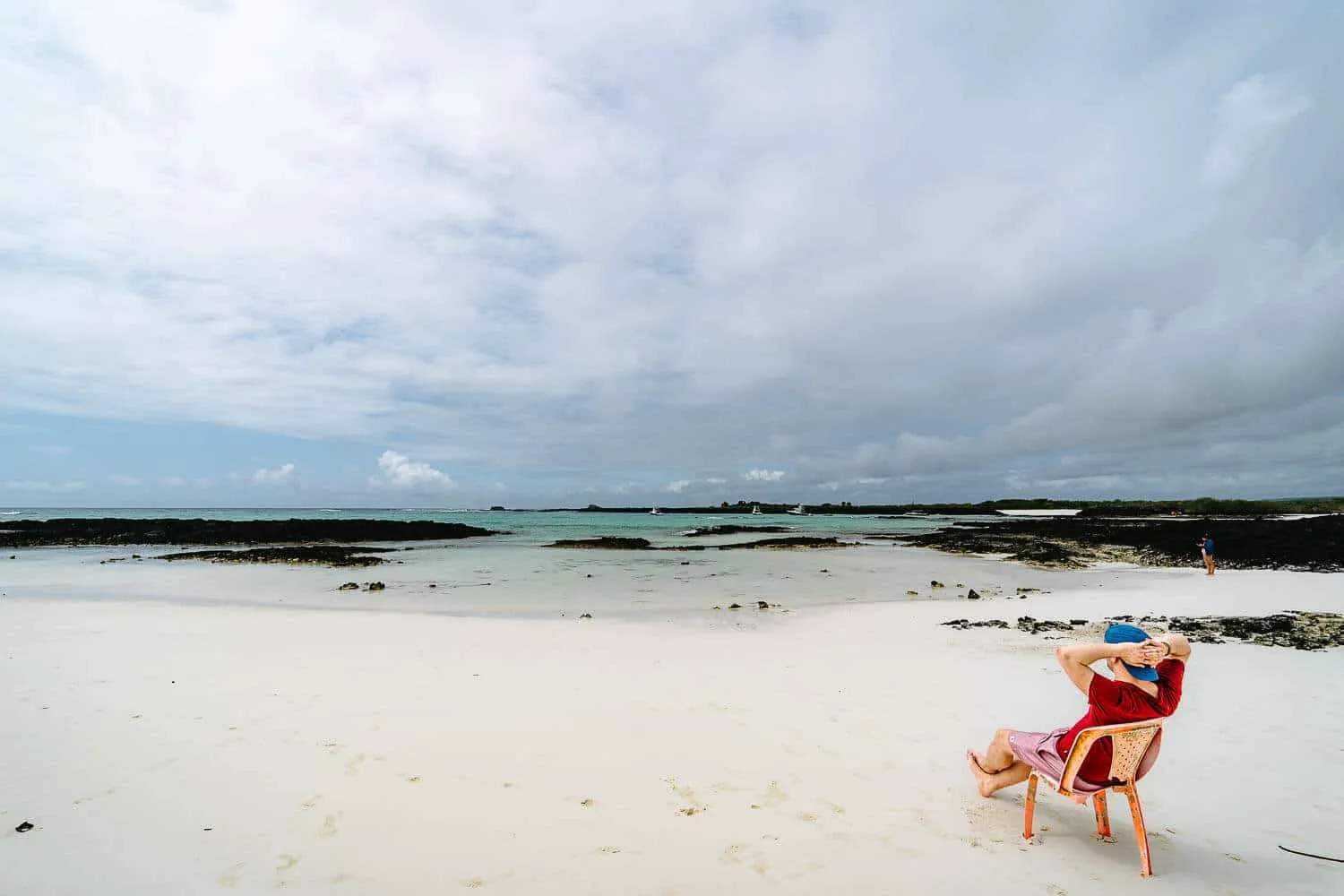 Sited on a plastic chair at Bahia Rosa Blanca beach in San Cristobal
