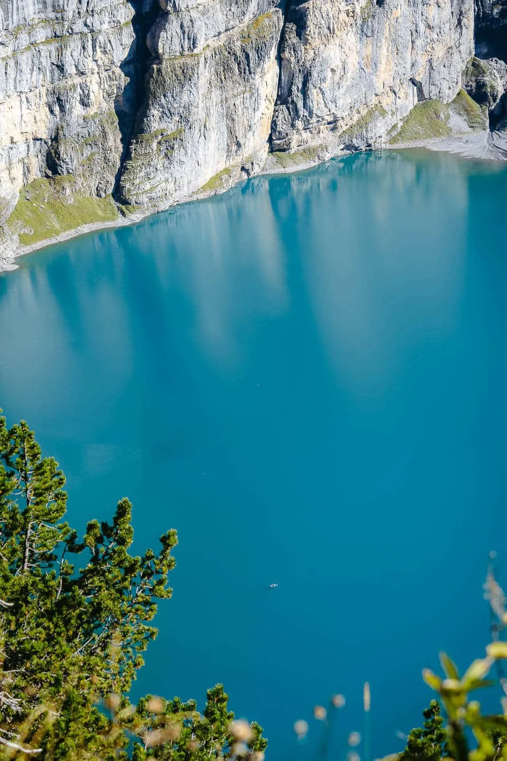 The scale of the Oeschinensee cliffs compared to a small boat in the water